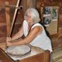 Hilleke maalt wat graan met de hand in de watermolen van Ginu&ccaron;iai